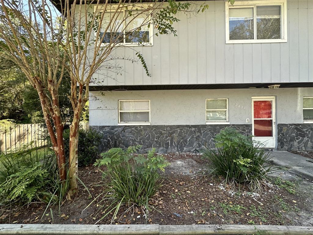 A two-story building exterior features gray siding, stone veneer, and a red front door — 2431 NW 4TH TERRACE UNIT 2431, GAINESVILLE, FL