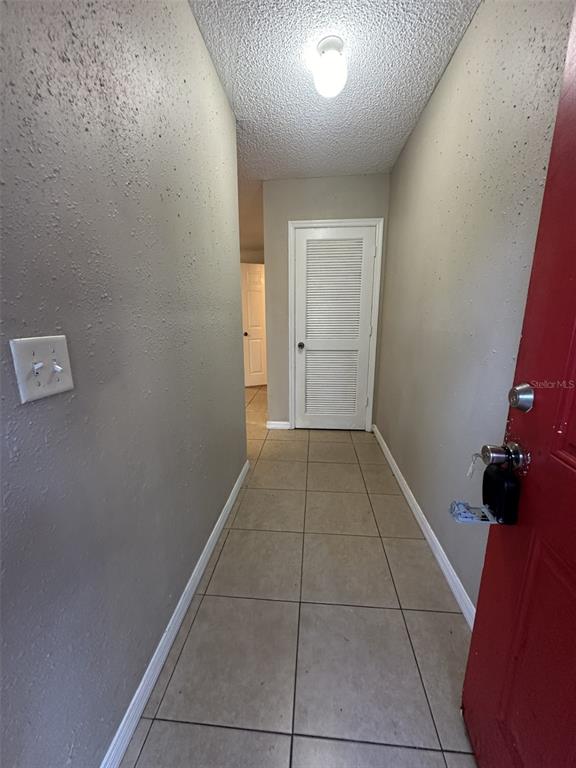 A tiled hallway leads to a white louvered door with a red door on the right — 2431 NW 4TH TERRACE UNIT 2431, GAINESVILLE, FL