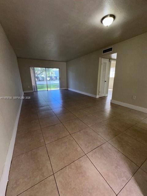 An empty room features beige tile flooring, a ceiling light, and a sliding glass door — 7500 SW 82nd St # G110, Miami FL 33143, MIAMI, FL