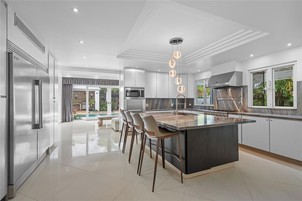 A modern kitchen features a large island with bar seating, stainless steel appliances, and white cabinetry — 18 PASEO LAS PALMAS, DORADO, PR, PR