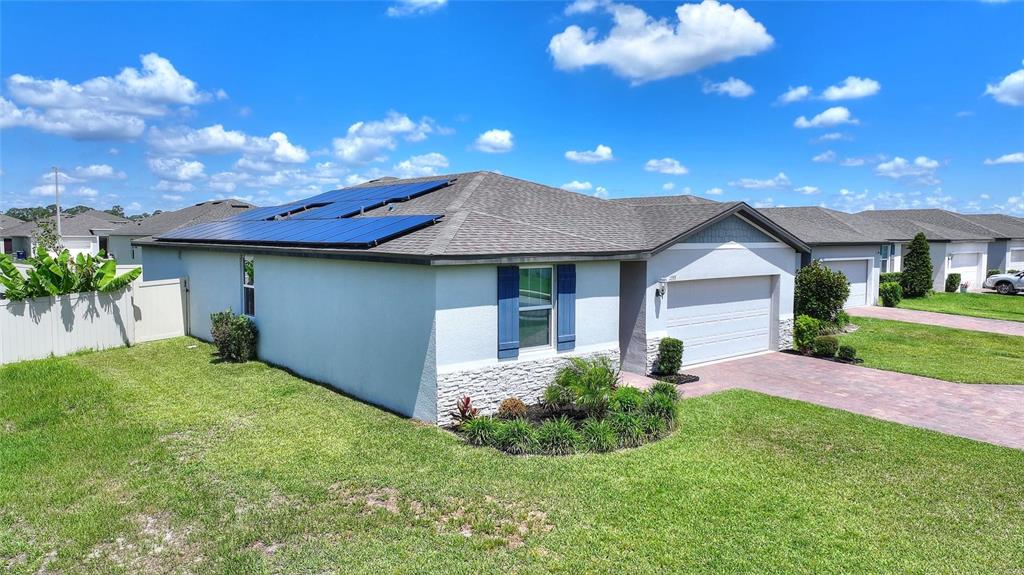 A single-story house with a paved driveway, solar panels on the roof, and landscaped yard — 1355 BENEVENTO DRIVE, WINTER HAVEN, FL