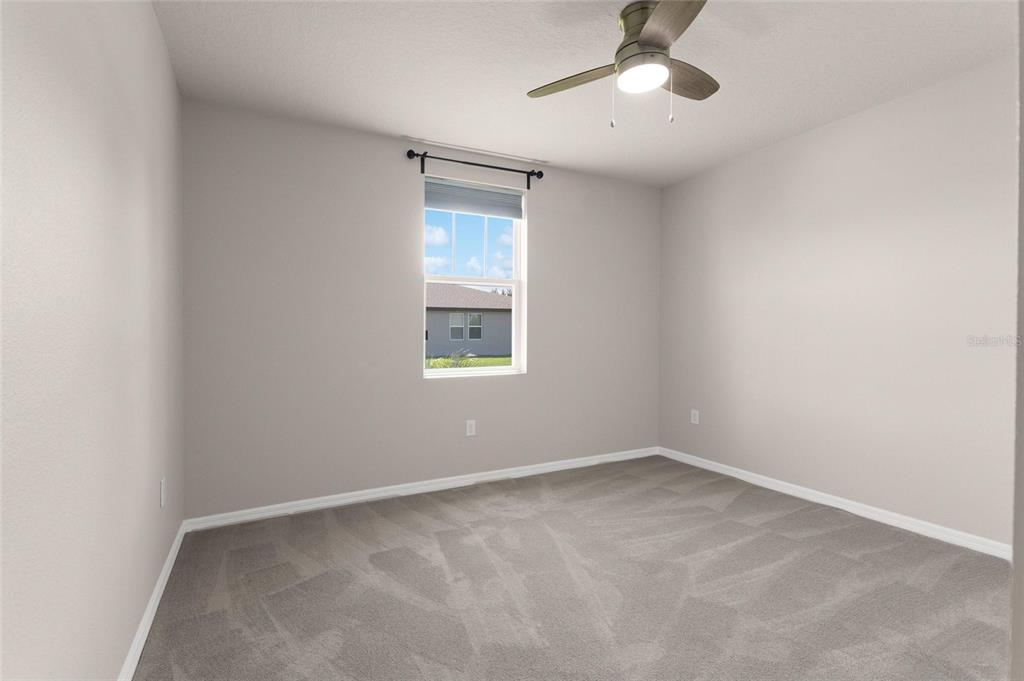 An empty bedroom features light gray walls, gray carpeting, a ceiling fan, and one window — 1355 BENEVENTO DRIVE, WINTER HAVEN, FL