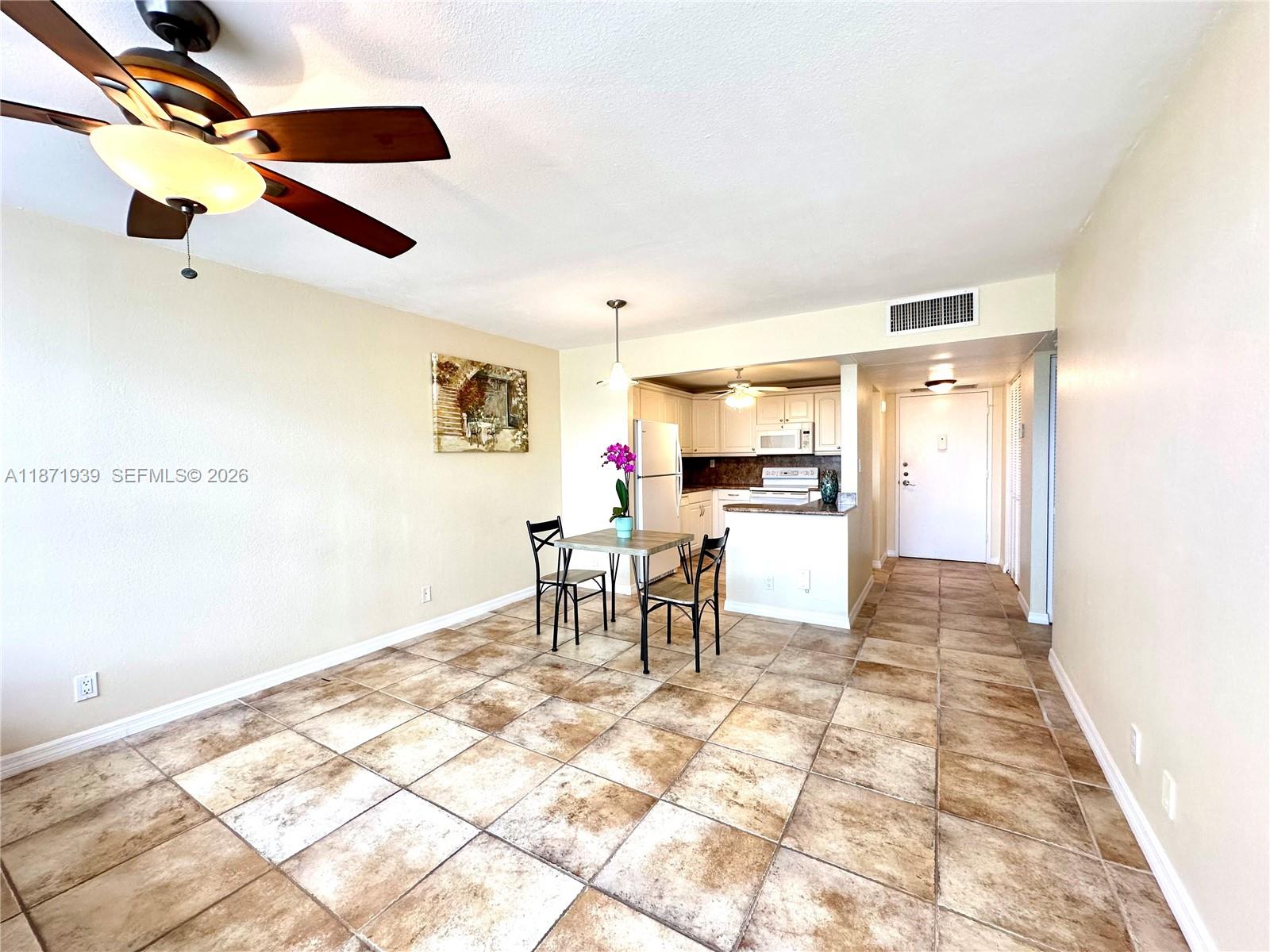 A dining area with tile floors and a ceiling fan opens into a small kitchen — 2771 Taft St # 302, Hollywood FL 33020, HOLLYWOOD, FL