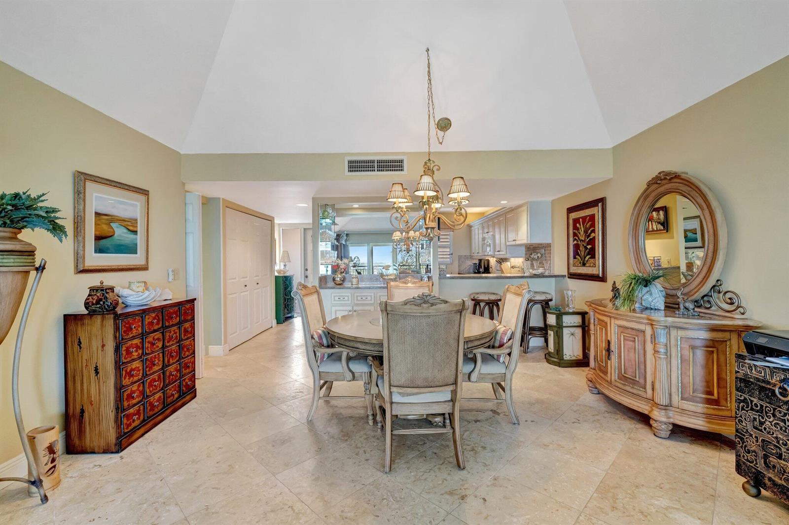 A dining room with a vaulted ceiling, stone tile floors, and a central chandelier — 1555 NE Ocean Boulevard # 402, Stuart FL 34996, STUART, FL