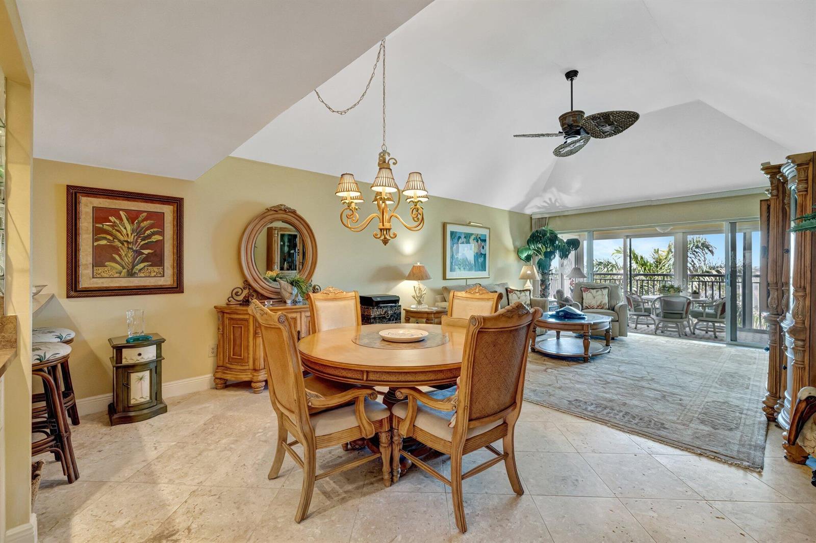 A dining area with a round table and chairs opens into a living room with balcony — 1555 NE Ocean Boulevard # 402, Stuart FL 34996, STUART, FL