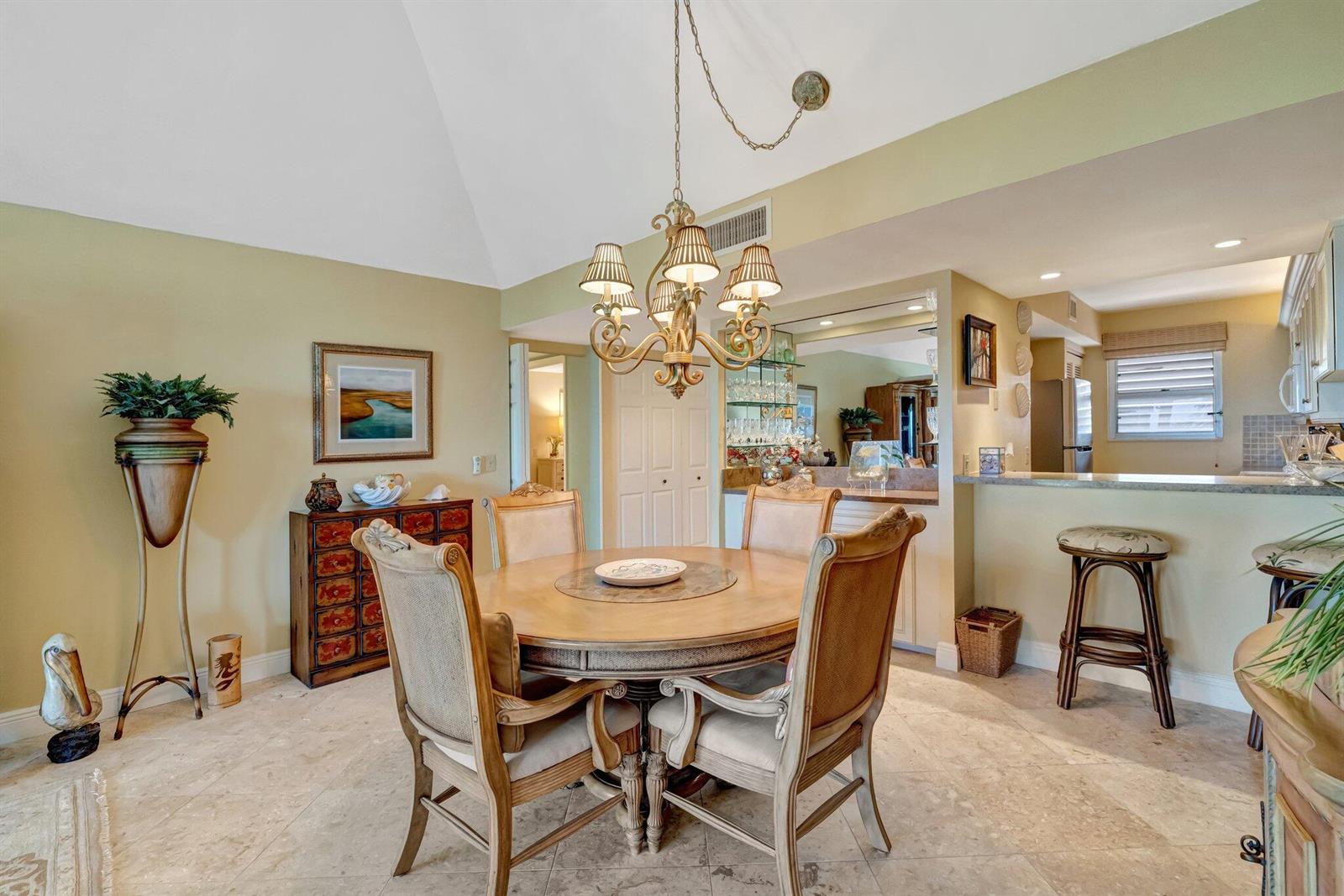 A dining area features a round wooden table, upholstered chairs, and a chandelier under a ceiling — 1555 NE Ocean Boulevard # 402, Stuart FL 34996, STUART, FL
