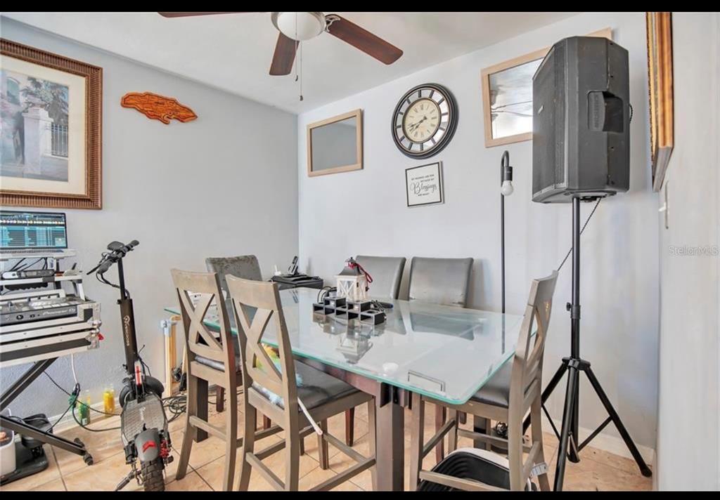 A dining room features a glass-topped table, gray chairs, a ceiling fan, and audio equipment — 5108 FIGWOOD LANE, ORLANDO, FL