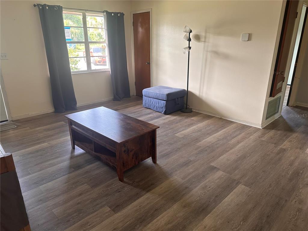 A living room features wood-look flooring, a television console, a coffee table, and a window — 401 CHERRY STREET, SOUTH DAYTONA, FL