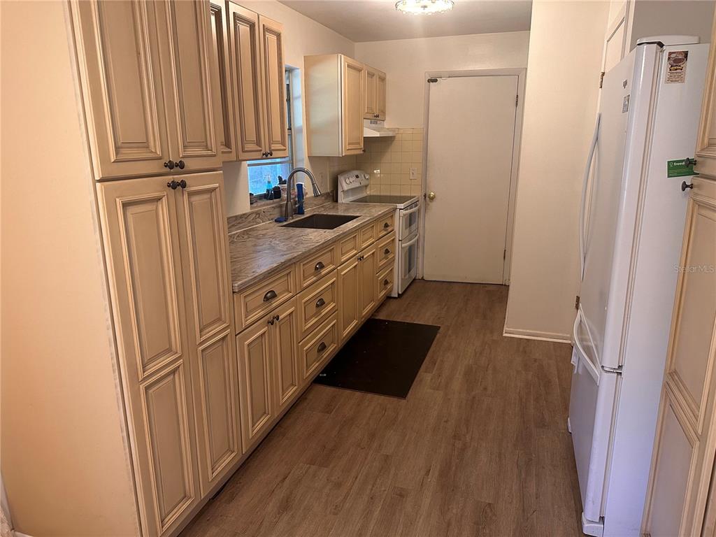 A kitchen features light wood cabinets, marble-patterned countertops, a stainless steel sink, and white appliances — 401 CHERRY STREET, SOUTH DAYTONA, FL