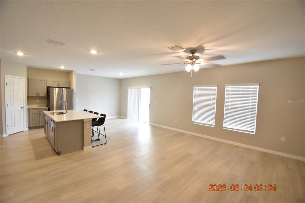 An open-concept kitchen and living area features light wood flooring, gray cabinets, and white countertops — 14468 MEADOW BIRD AVENUE, RIVERVIEW, FL