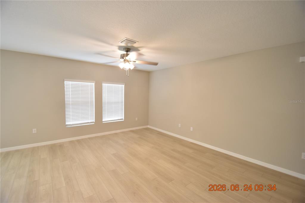 An empty room with light wood-look flooring, beige walls, and a ceiling fan — 14468 MEADOW BIRD AVENUE, RIVERVIEW, FL