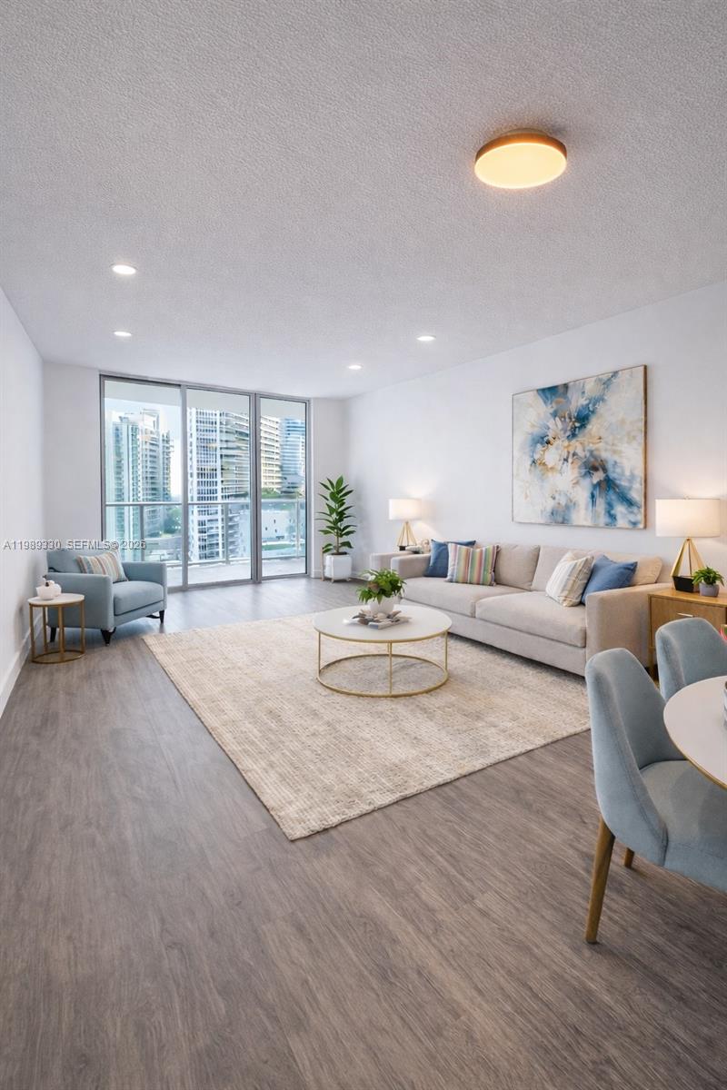 A bright living room features light wood flooring, a neutral sofa, and floor-to-ceiling windows — 1155 Brickell Bay Dr # 1705, Miami FL 33131, MIAMI, FL