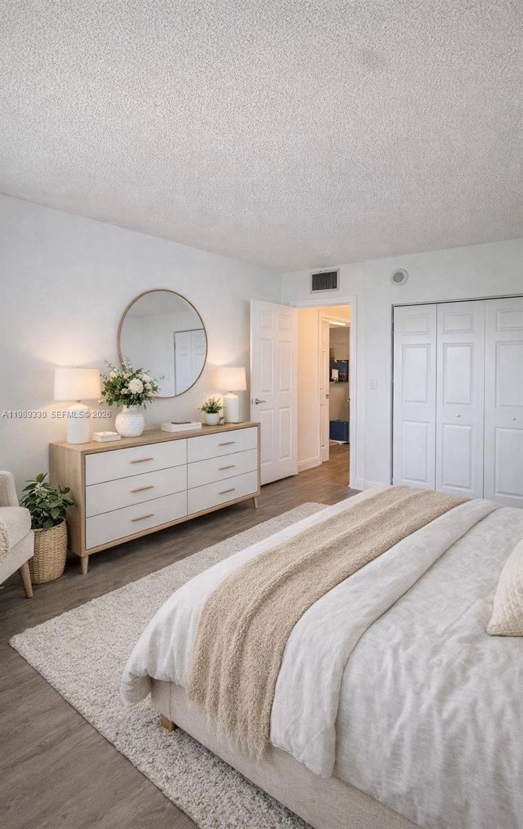 A bedroom features a white dresser, a round mirror, and a bed with neutral bedding — 1155 Brickell Bay Dr # 1705, Miami FL 33131, MIAMI, FL
