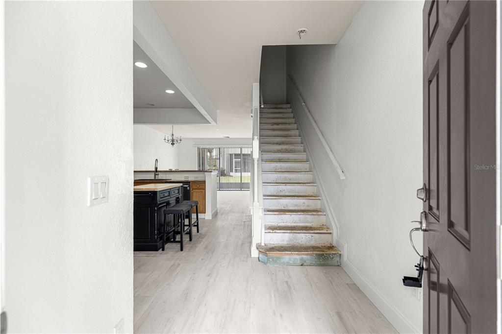 An entryway leads to a kitchen with a dark island and stairs to the second floor — 4131 SW 51ST CIRCLE, OCALA, FL