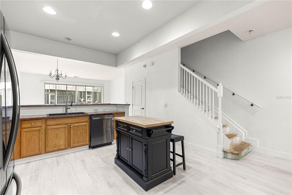 A kitchen features wood cabinets, a black island, stainless steel appliances, and a staircase — 4131 SW 51ST CIRCLE, OCALA, FL