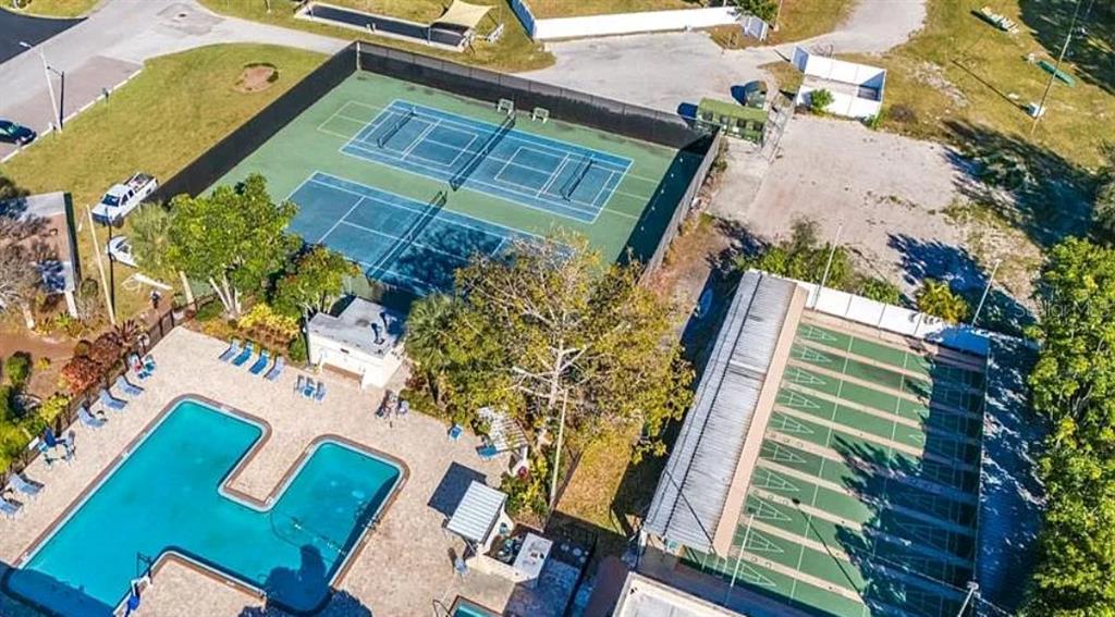 A covered parking structure with a blue privacy screen stands in an asphalt parking lot — 5925 TERRACE PARK DRIVE N UNIT 111, ST PETERSBURG, FL