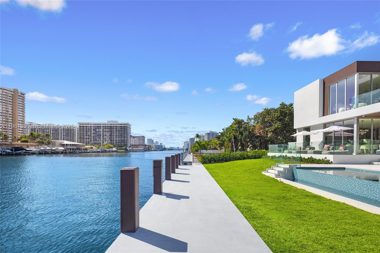 A modern waterfront house features a swimming pool, a grassy lawn, and a concrete dock — 503 Palm Dr, Hallandale Beach FL 33009, HALLANDALE BEACH, FL