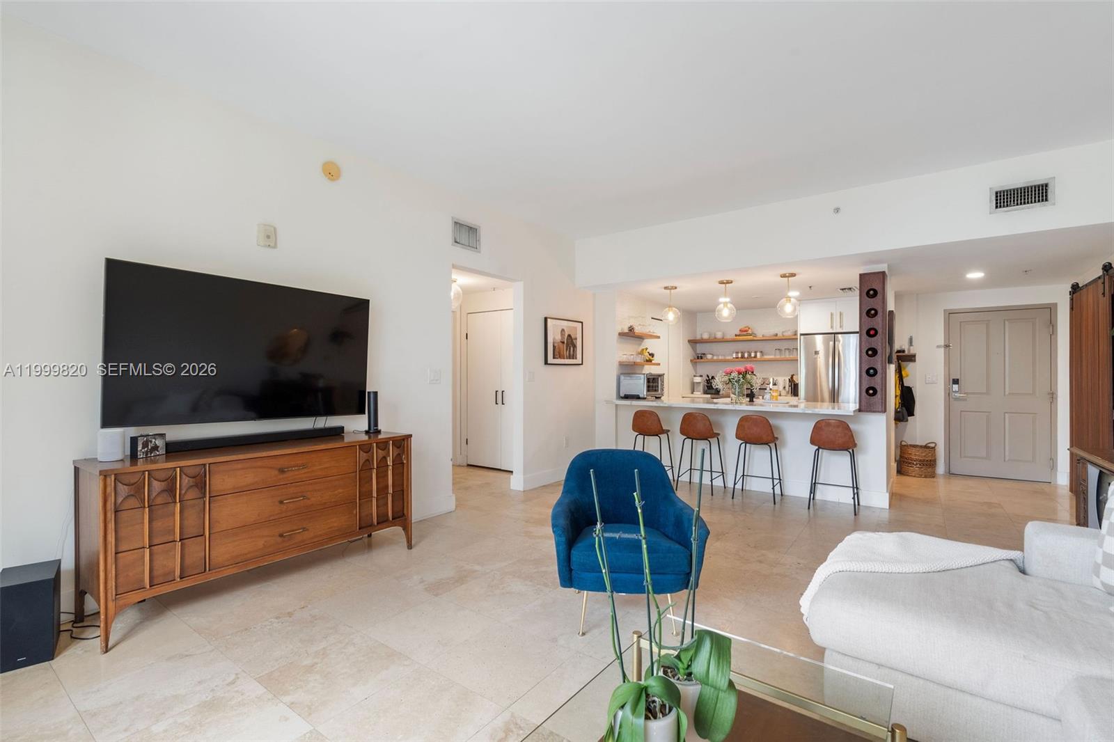A living room features a large television on a wooden console and an open kitchen — 2650 SW 37th Ave # 406, Miami FL 33133, MIAMI, FL