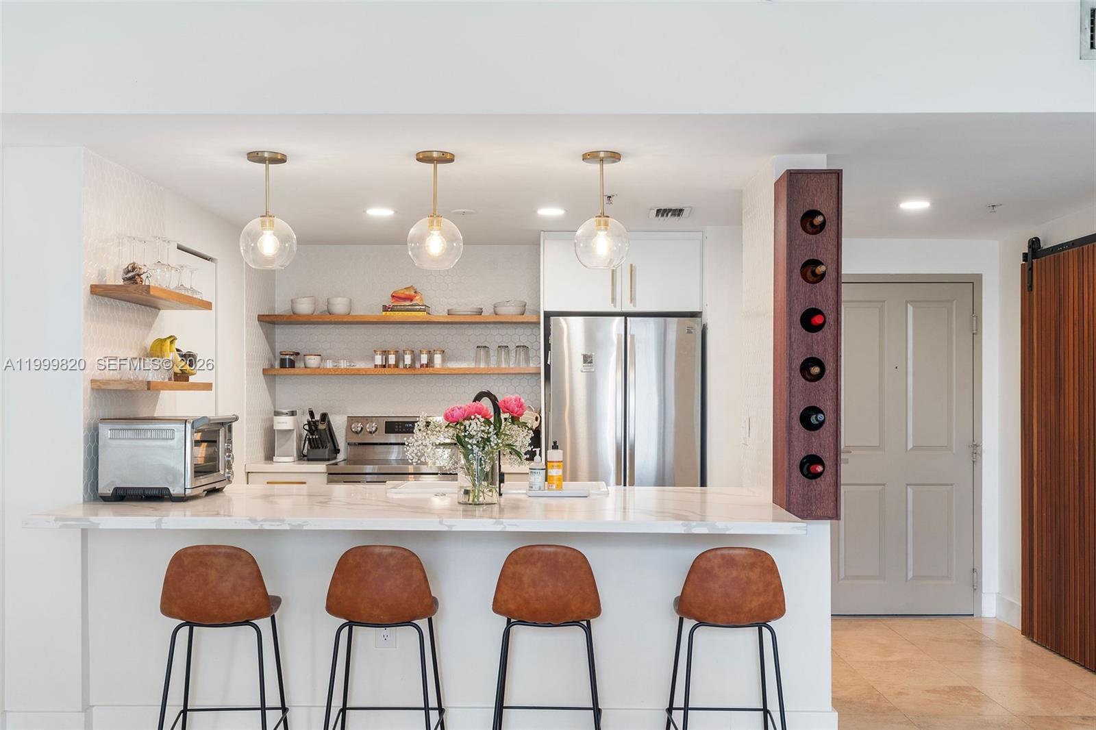 A modern kitchen features a marble-topped island with four bar stools and open wooden shelving — 2650 SW 37th Ave # 406, Miami FL 33133, MIAMI, FL