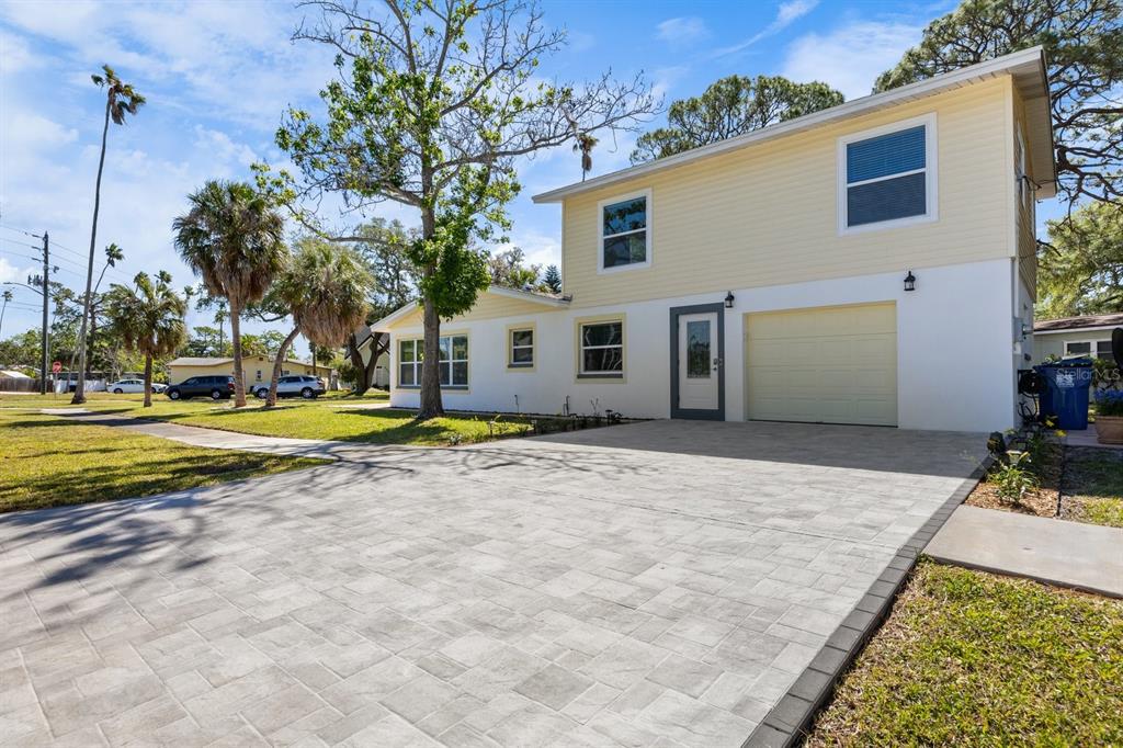 A two-story house with yellow siding, a white stucco lower level, and a paved driveway — 4038 HARRISBURG, ST PETERSBURG, FL