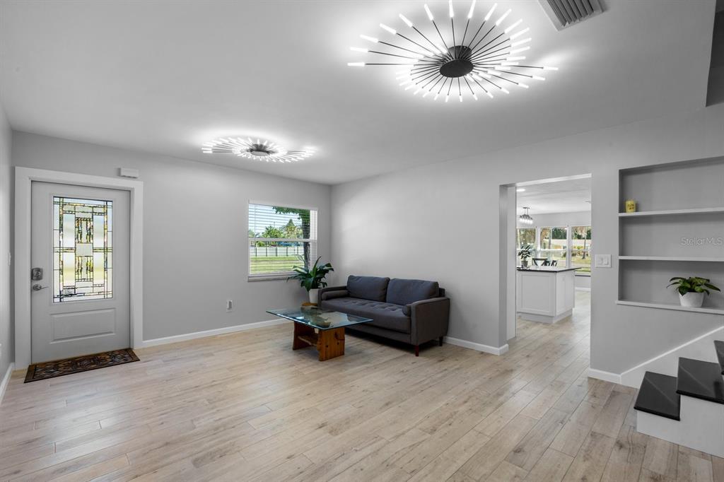 A living room features light wood flooring, a gray sofa, and two modern starburst light fixtures — 4038 HARRISBURG, ST PETERSBURG, FL