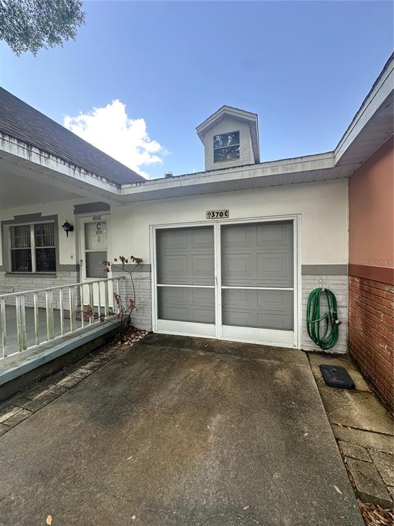 A concrete driveway leads to a garage with a screen door and a small dormer window — 9370 SW 85TH TERRACE UNIT C, OCALA, FL