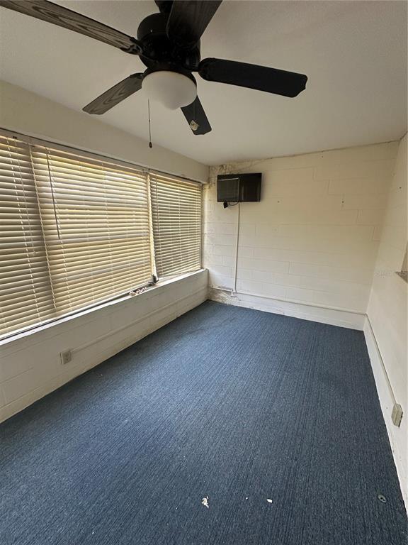 A sunroom with blue carpeting, a ceiling fan, and white painted concrete block walls — 9370 SW 85TH TERRACE UNIT C, OCALA, FL