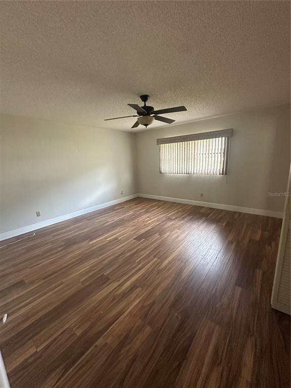 An empty room features wood-look flooring, a ceiling fan, and a window with blinds — 9370 SW 85TH TERRACE UNIT C, OCALA, FL
