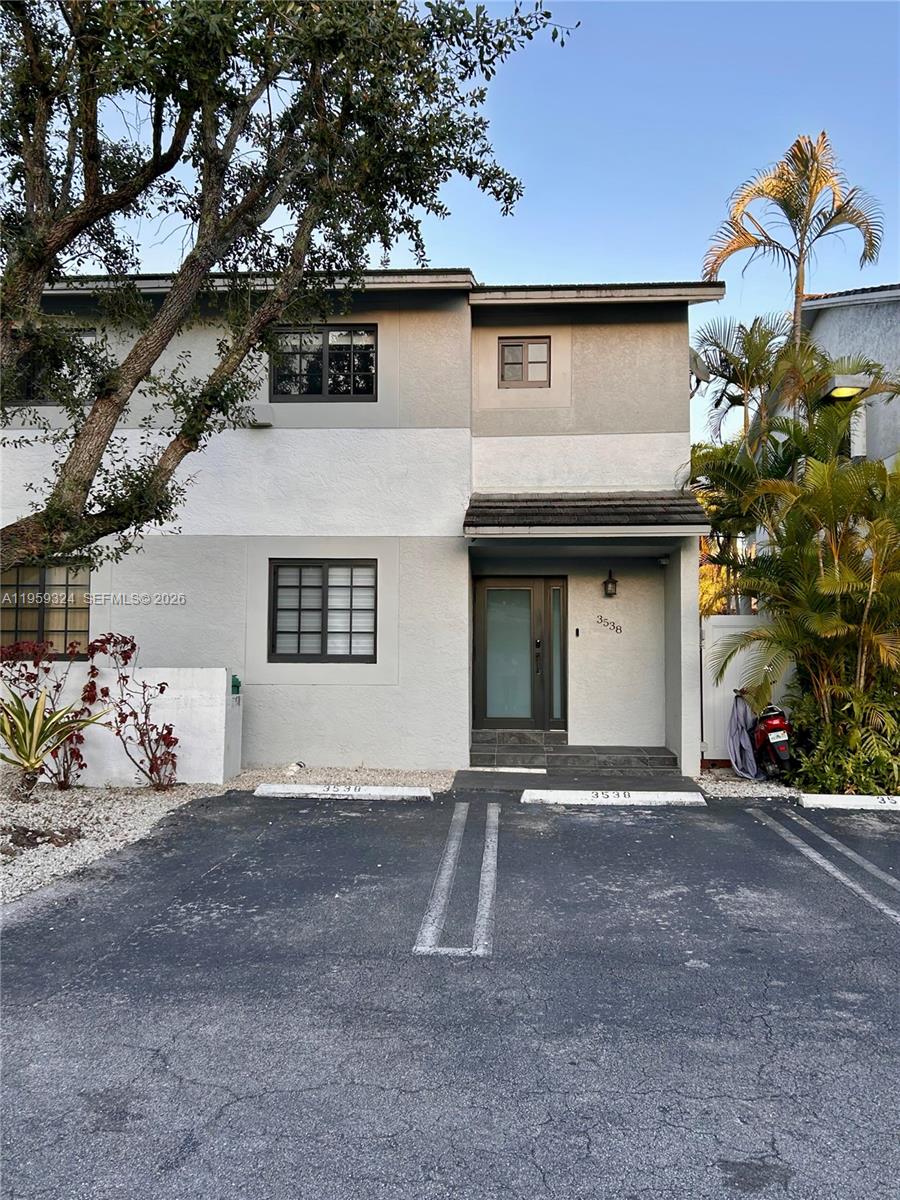 The exterior of a two-story townhouse features gray and white stucco walls with parking spaces — 3538 SW 17th St # 1B, Miami FL 33145, MIAMI, FL