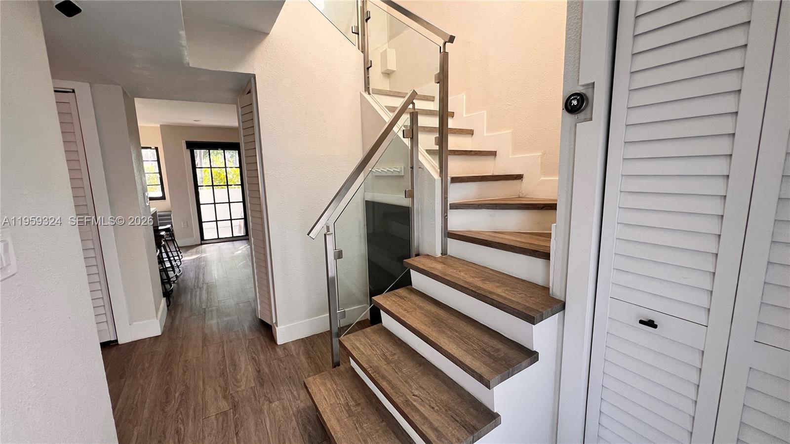 A staircase with wood treads and a glass railing leads to an upper level — 3538 SW 17th St # 1B, Miami FL 33145, MIAMI, FL