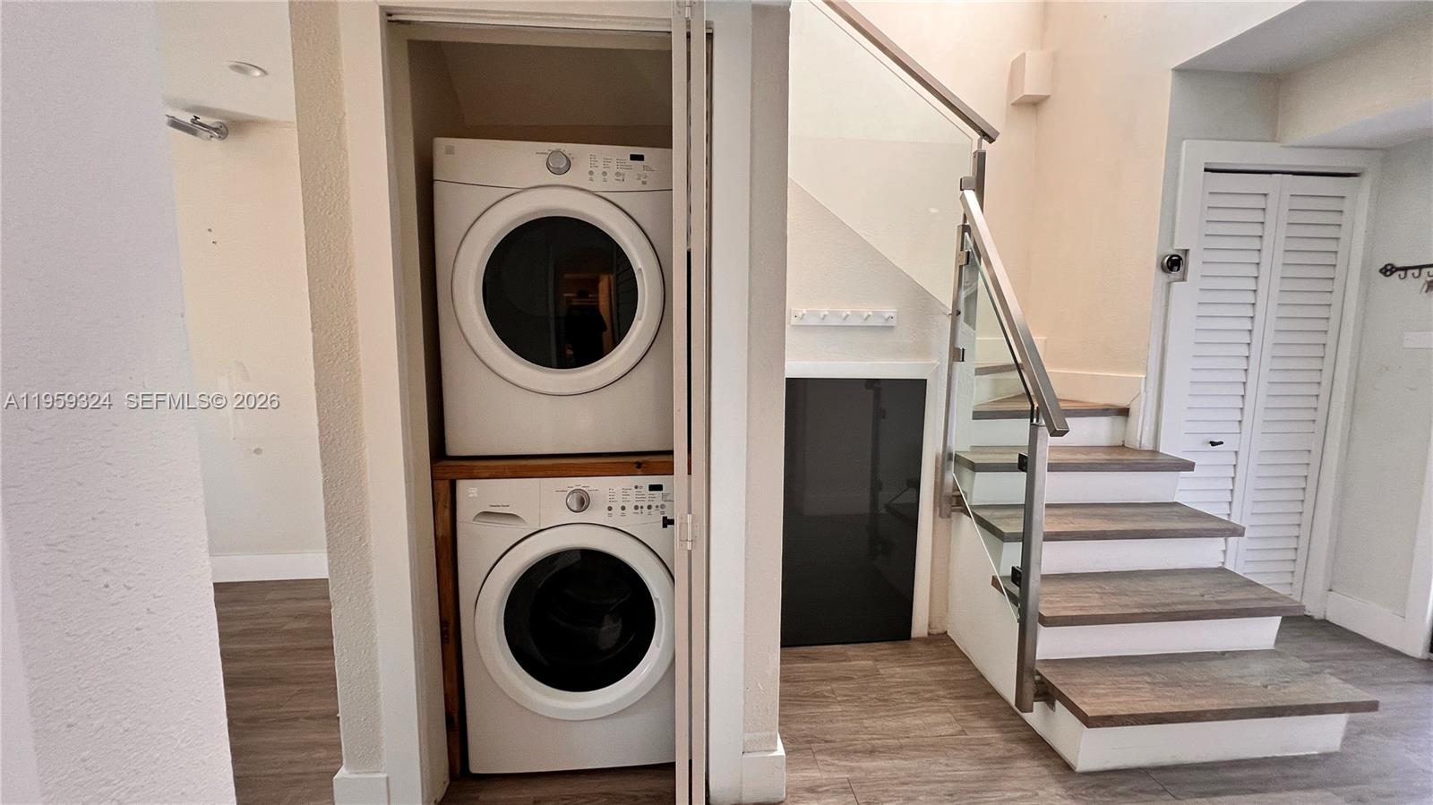 A stacked washer and dryer unit sits next to a staircase with glass railings — 3538 SW 17th St # 1B, Miami FL 33145, MIAMI, FL
