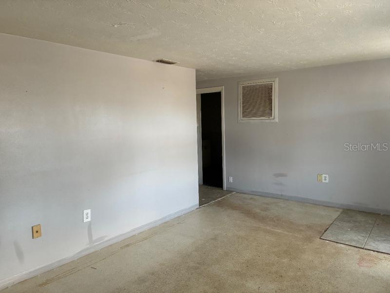 An empty room with light gray walls, a concrete floor, and a doorway leading elsewhere — 4816 PANORAMA AVENUE, HOLIDAY, FL