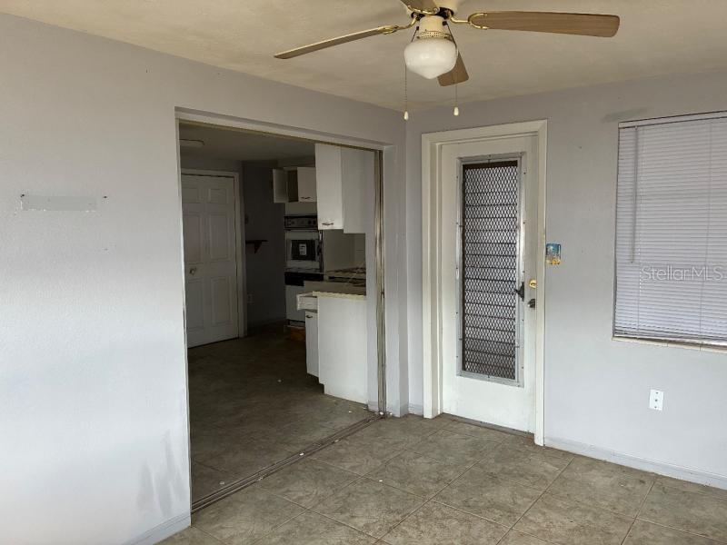 A tiled room with a ceiling fan leads into a kitchen through a wide doorway — 4816 PANORAMA AVENUE, HOLIDAY, FL