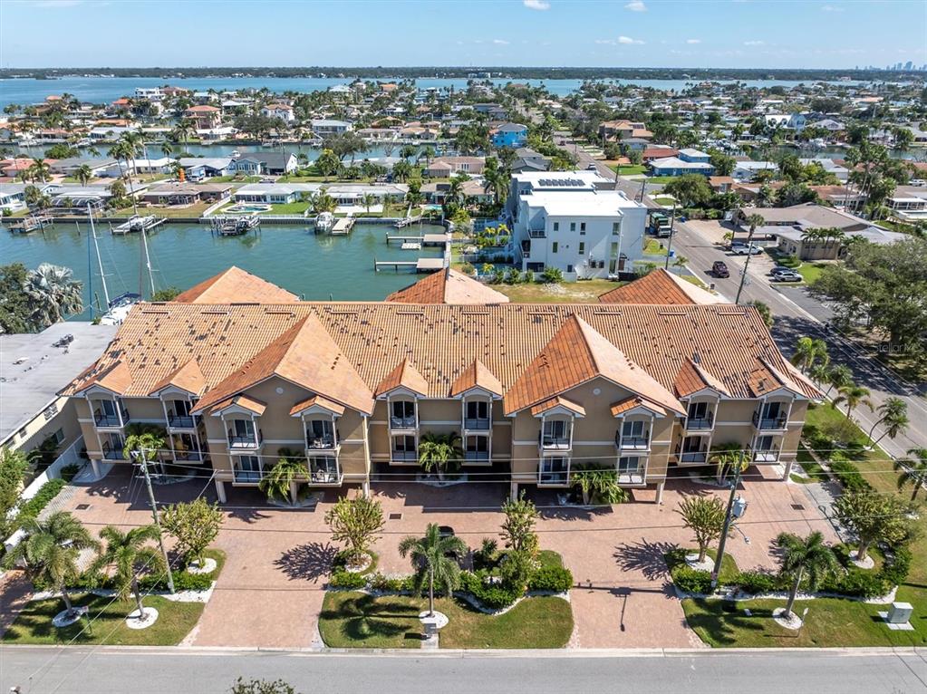 An aerial view shows a multi-story tan building with a tiled roof near a canal — 300 CAPRI BOULEVARD UNIT 6, TREASURE ISLAND, FL