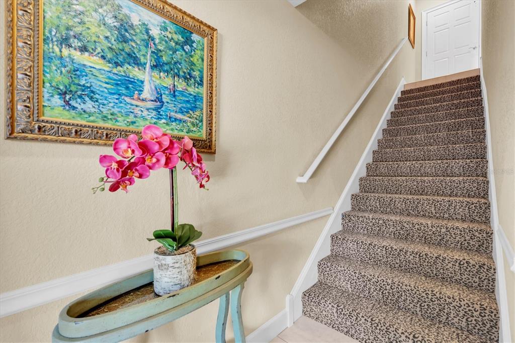 A staircase with leopard-print carpet leads to a landing with a white door — 300 CAPRI BOULEVARD UNIT 6, TREASURE ISLAND, FL