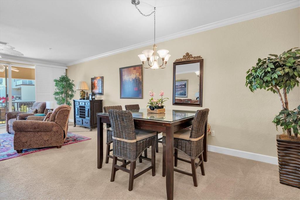 A dining area with a glass-topped table and wicker chairs sits beside a living room — 300 CAPRI BOULEVARD UNIT 6, TREASURE ISLAND, FL