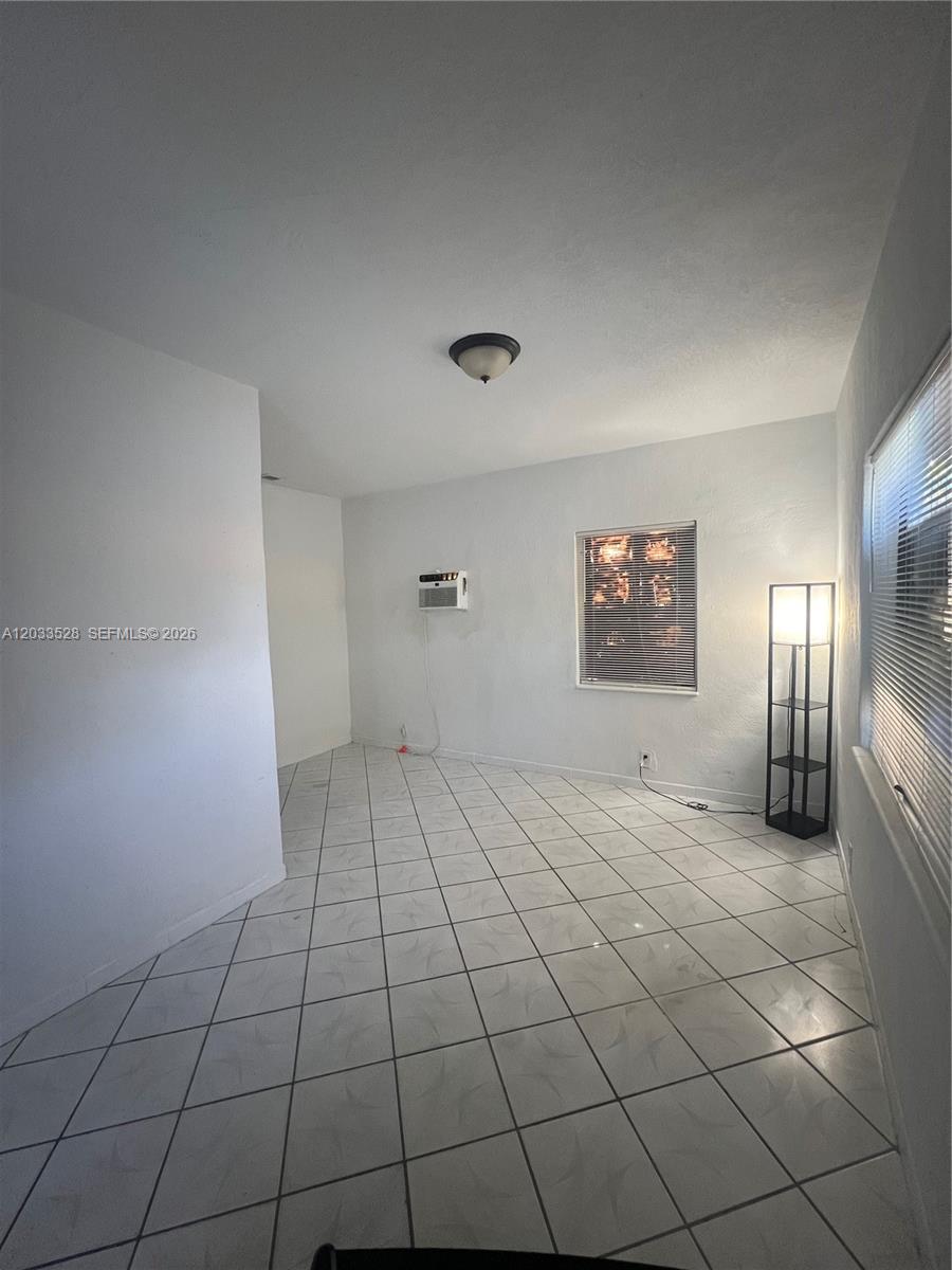 A room with white walls, tiled floors, a window air conditioner, and a floor lamp — 1060 NW 116th St # 4, Miami FL 33168, MIAMI, FL