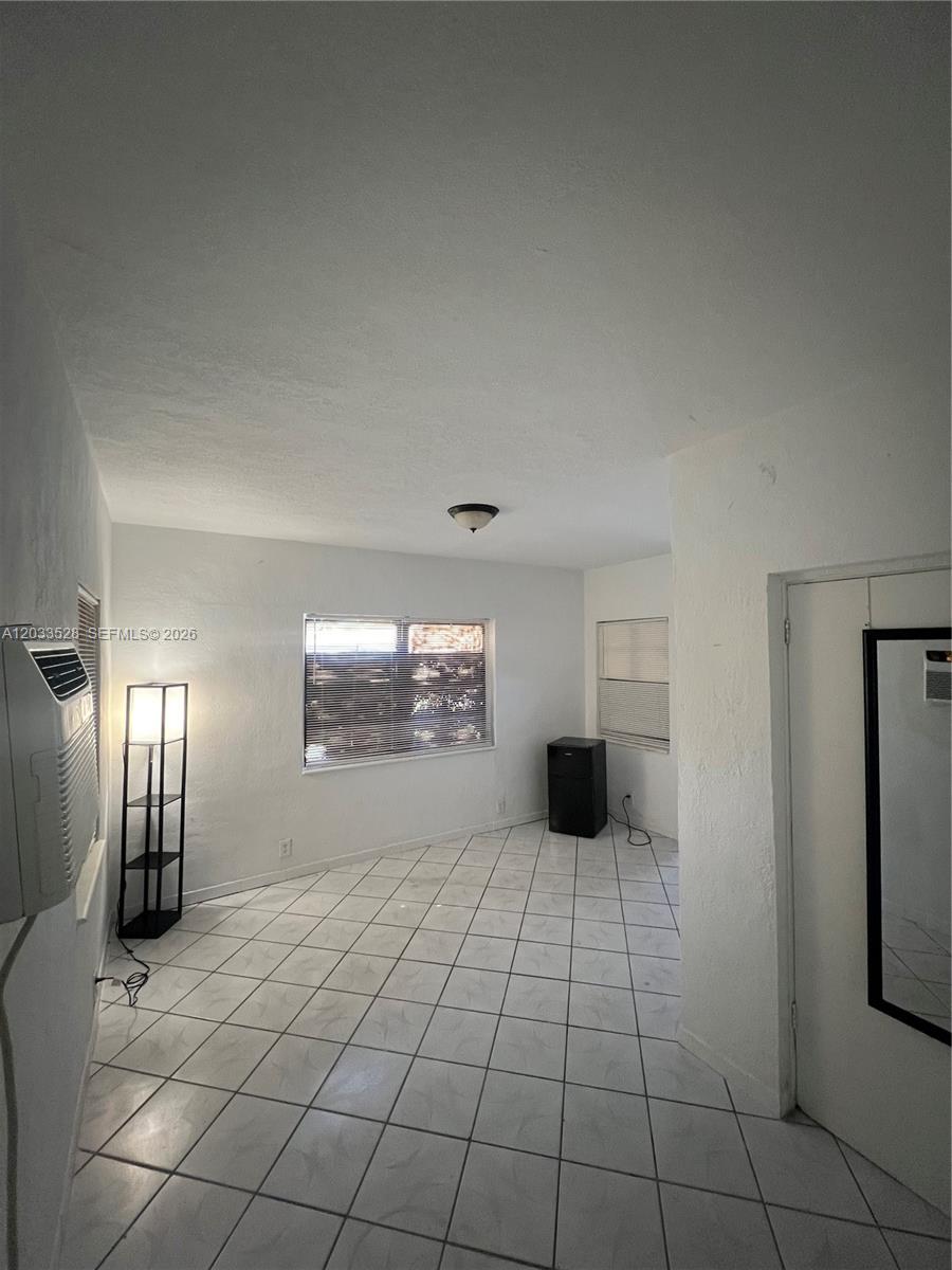 A room with white walls, tiled floors, a window with blinds, and a floor lamp — 1060 NW 116th St # 4, Miami FL 33168, MIAMI, FL