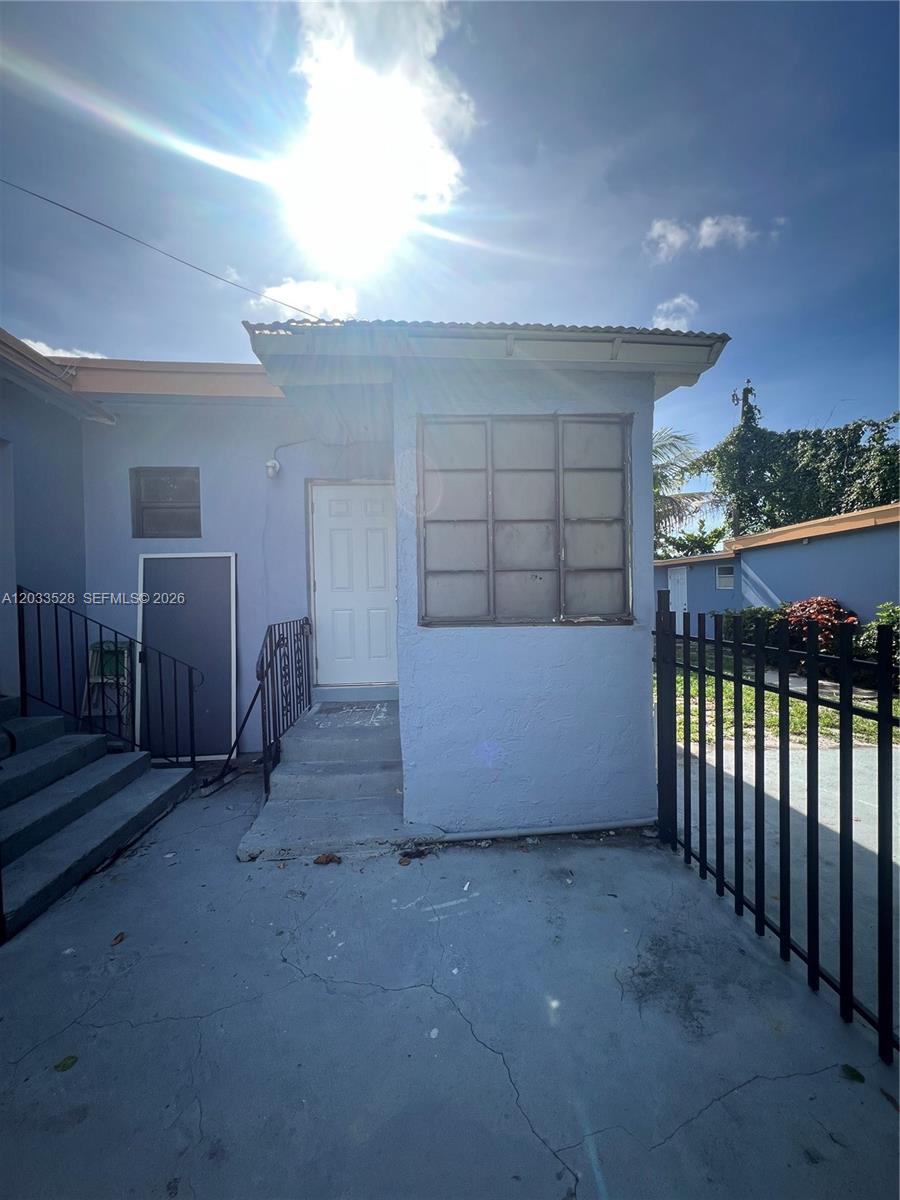 An exterior view shows a light blue building with a concrete porch and metal railings — 1060 NW 116th St # 4, Miami FL 33168, MIAMI, FL