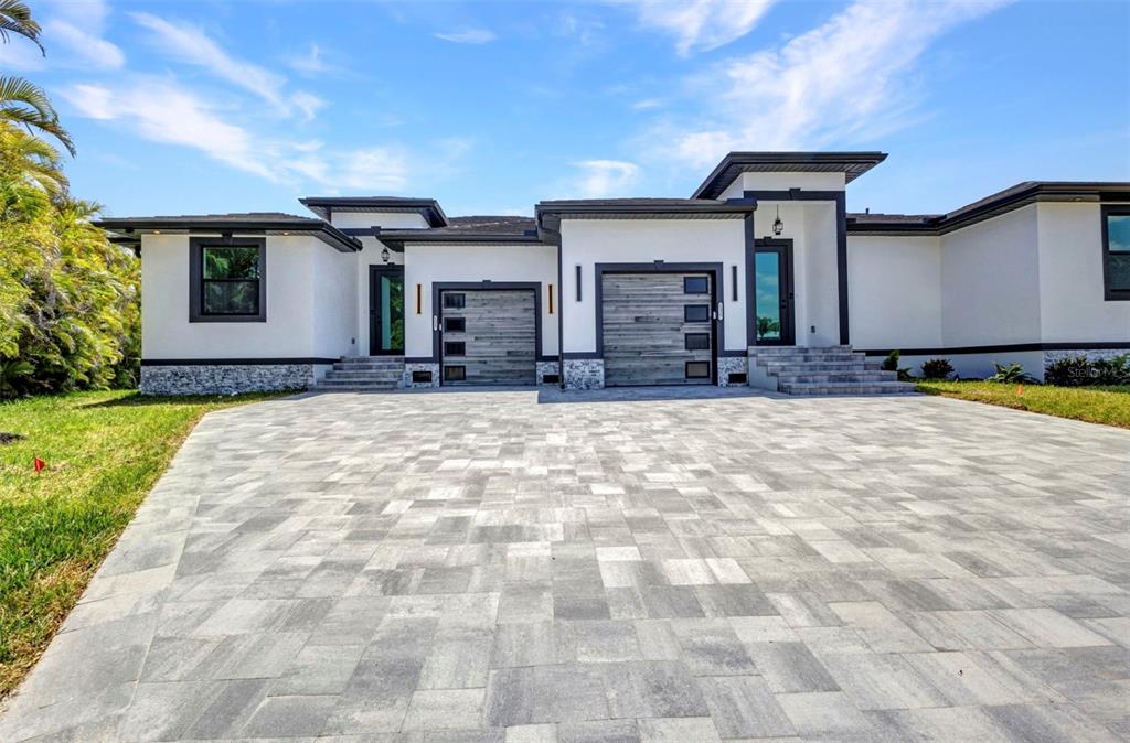 A modern single-story house with a paved driveway, two garage doors, and white stucco walls — 1327 WESLEY DRIVE, PUNTA GORDA, FL