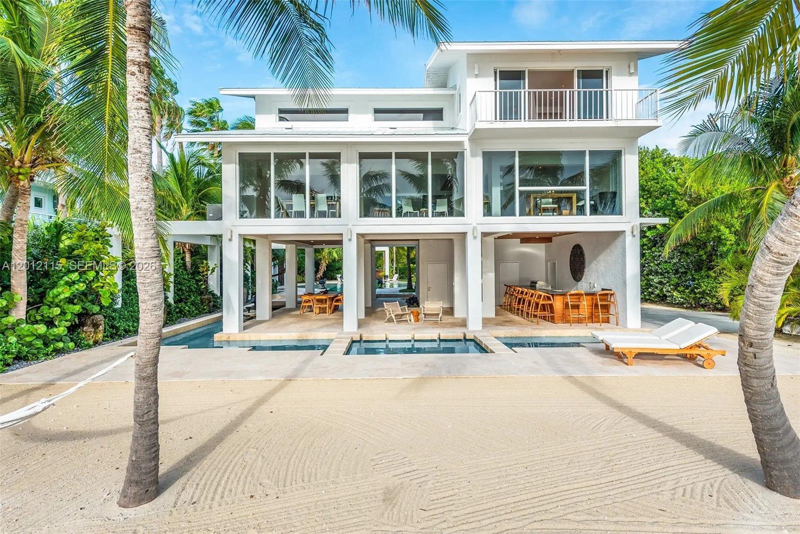 A three-story white beach house features a ground-level pool, outdoor bar, and sandy yard — 60 Ocean Front Dr, Key Largo FL 33037, KEY LARGO, FL