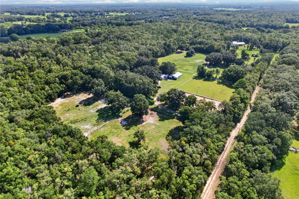 An aerial view shows a rural property with cleared pastures, wooded areas, and several buildings — 9813 NW STATE ROAD 45, HIGH SPRINGS, FL