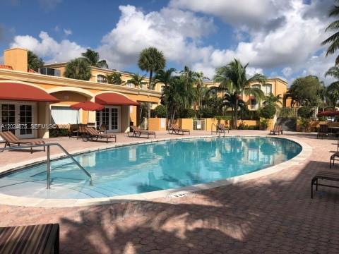 A swimming pool sits in front of a multi-story building with palm trees — 18111 NW 68th Ave # F203, Hialeah FL 33015, HIALEAH, FL