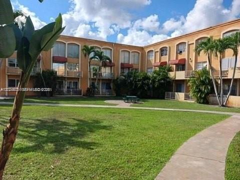 A multi-story apartment building with balconies overlooks a grassy courtyard with palm trees — 18111 NW 68th Ave # F203, Hialeah FL 33015, HIALEAH, FL