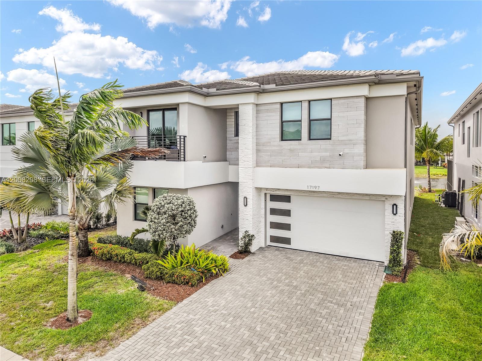 A two-story modern house features a white garage, stone accents, and a balcony — 17197 Teton River Rd # 0, Boca Raton FL 33496, BOCA RATON, FL