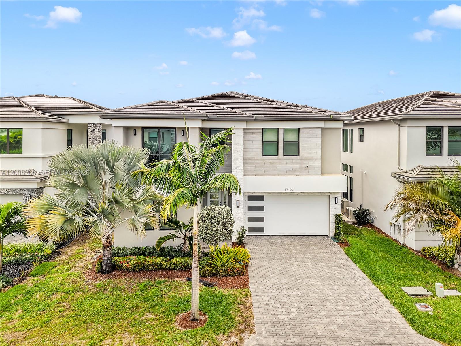 A two-story modern house with a paved driveway, palm trees, and a white garage door — 17197 Teton River Rd # 0, Boca Raton FL 33496, BOCA RATON, FL