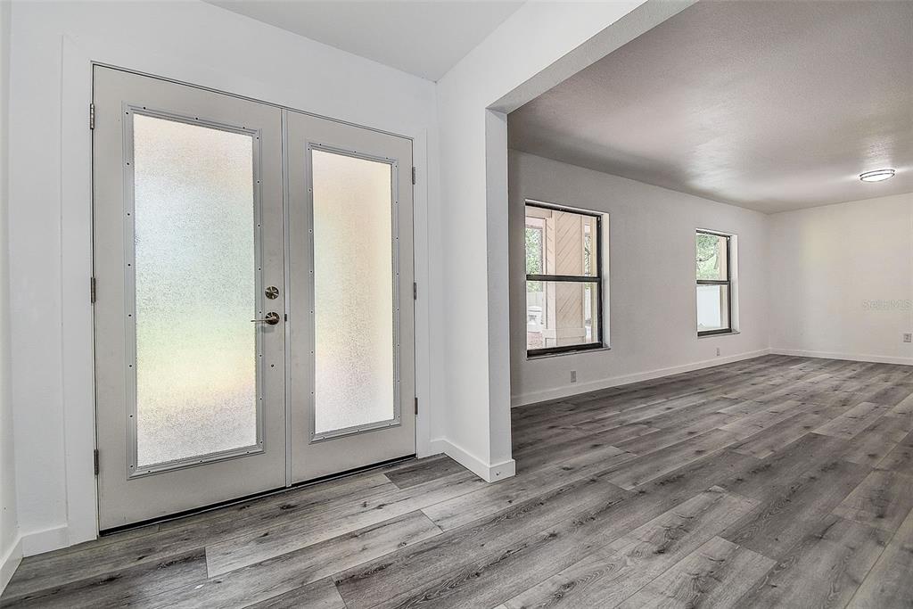A bright room with gray wood-look flooring and a double glass-paneled front door — 9404 W HAMILTON AVENUE, TAMPA, FL