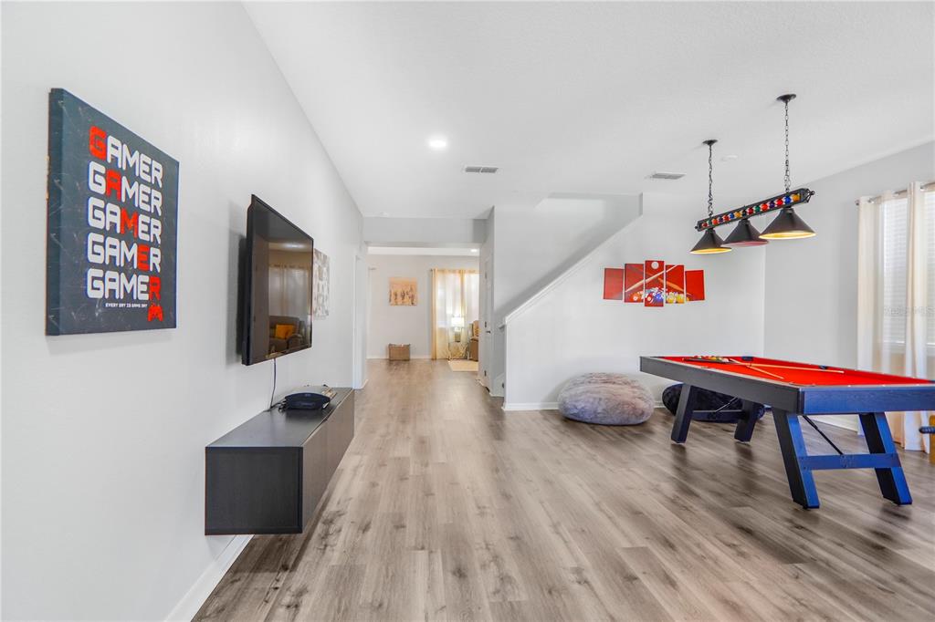 A game room features a pool table, wall-mounted television, and wood-look flooring — 436 ALDRIDGE LANE, DAVENPORT, FL