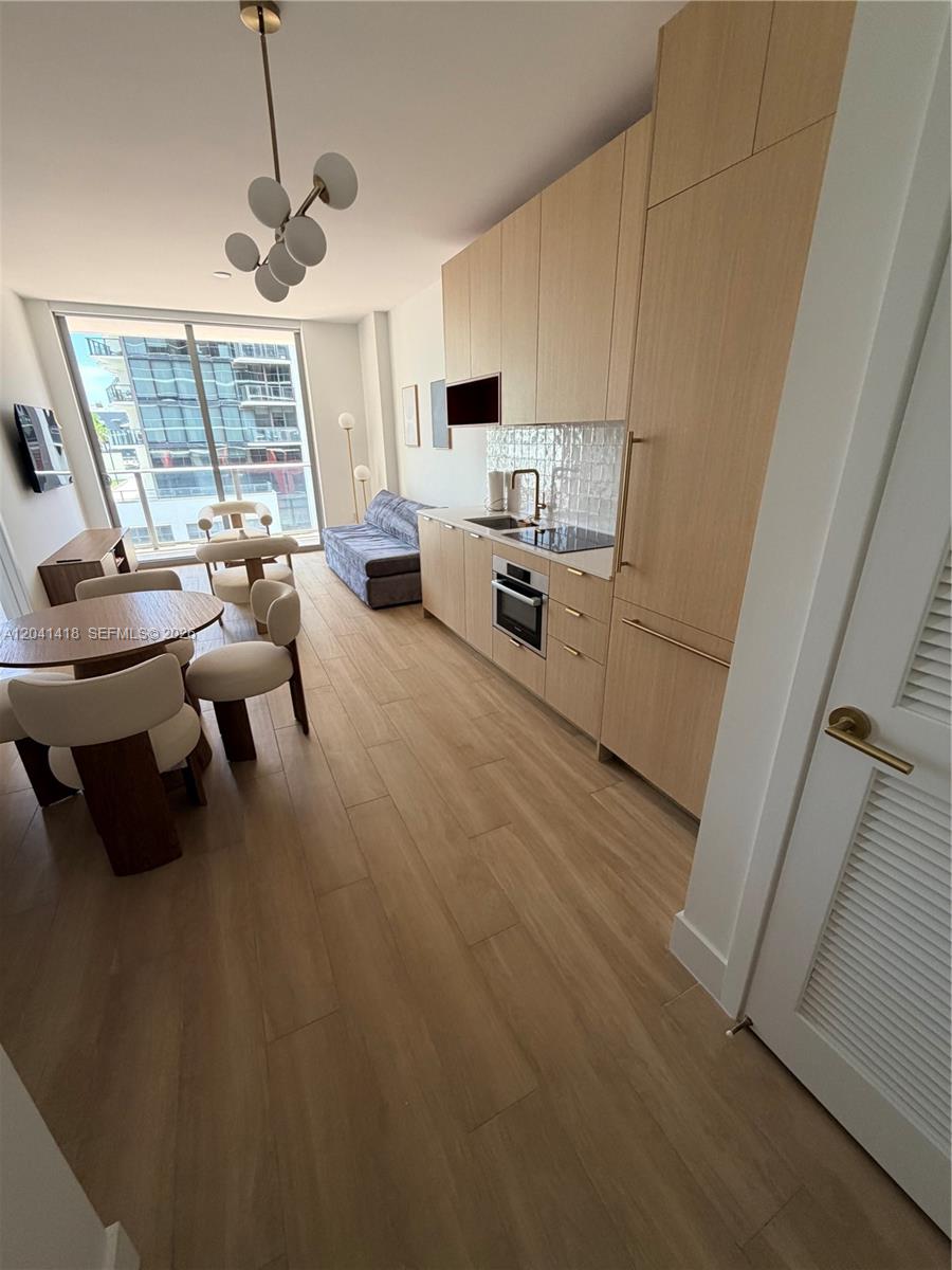 A modern studio apartment features light wood cabinetry, a dining area, and a balcony view — 90 NE 32nd St # 707, Miami FL 33137, MIAMI, FL