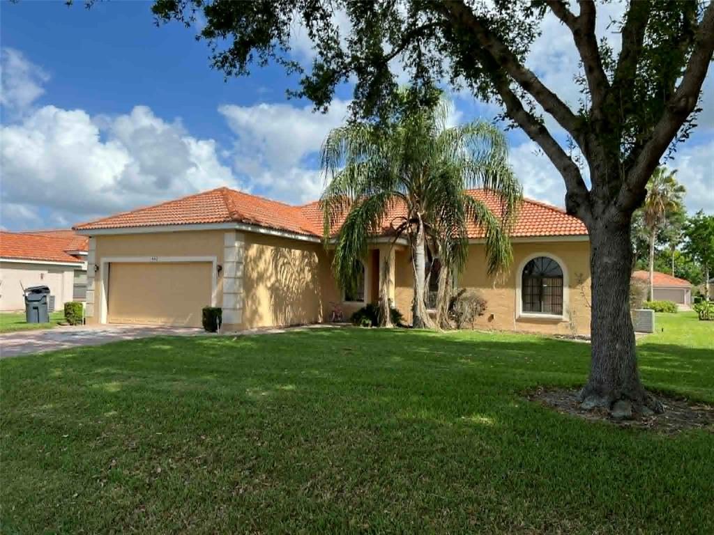 A single-story house with a tan stucco exterior, tile roof, and a two-car garage — 442 CARAWAY DRIVE, KISSIMMEE, FL
